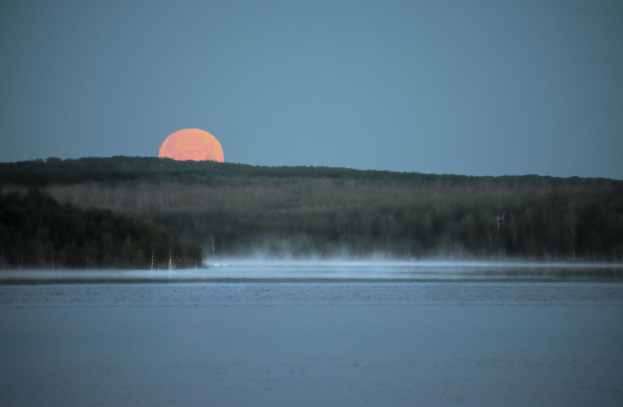 A red moon setting over a lake. Moonlight.